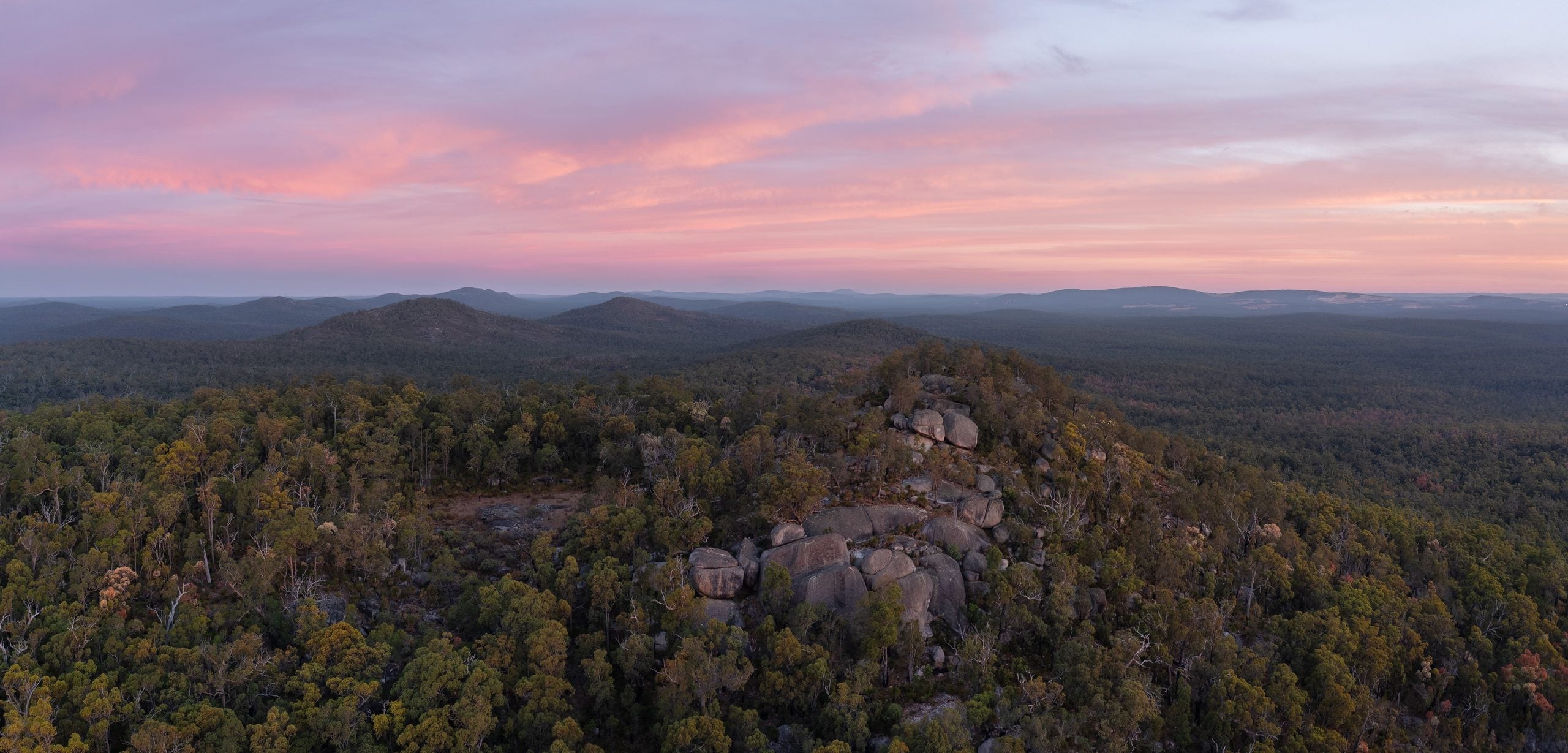 Abenddämmerung mit rosa gefärbtem Himmel über den bewaldeten Jarrah-Hügeln bei Jarrahdale, Westaustralien